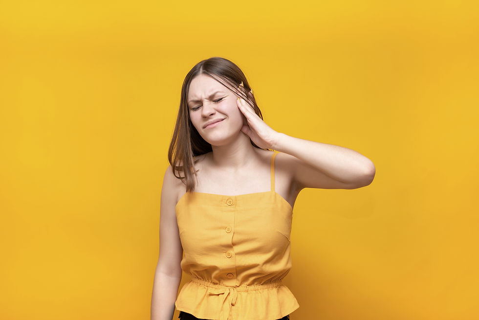 young woman with hand on ear from pain of tinnitus