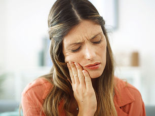 woman holding jaw due to TMJ pain