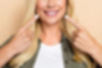 attractive woman pointing to her healthy smile shows the benefits of restorative dentistry at Hygge Laser Dentistry in Seattle