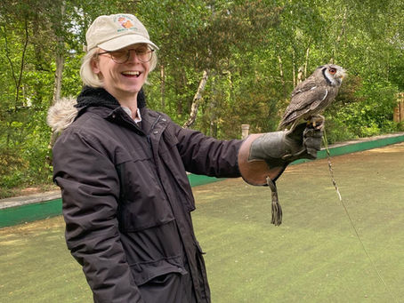 Myles holds a small owl, smiling.