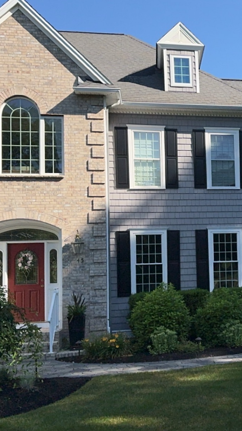 Brick colonial home with clean windows and black shutters