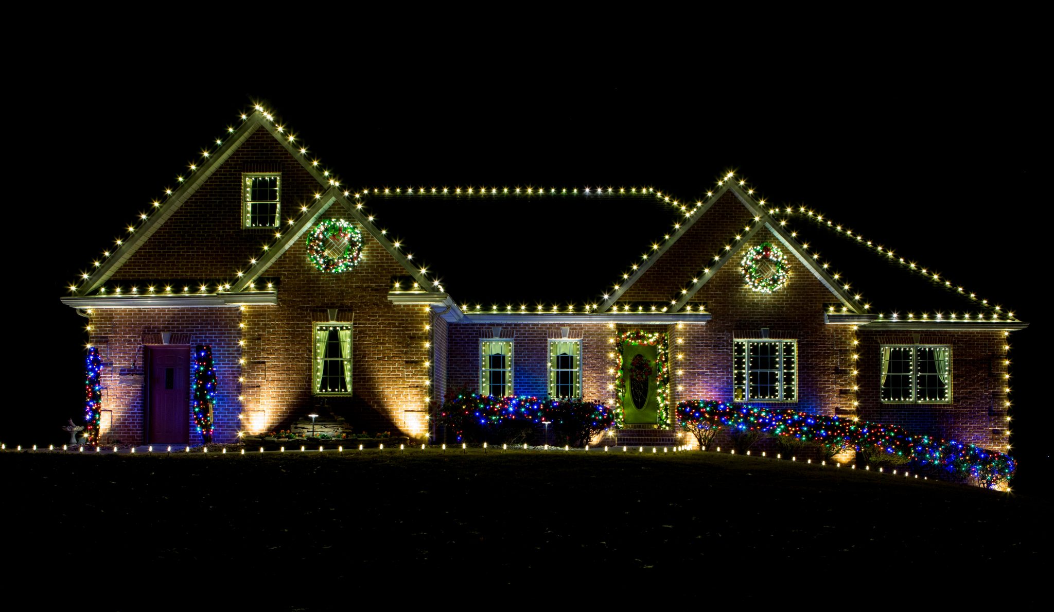 Professionally installed Christmas lights on a home roofline at night