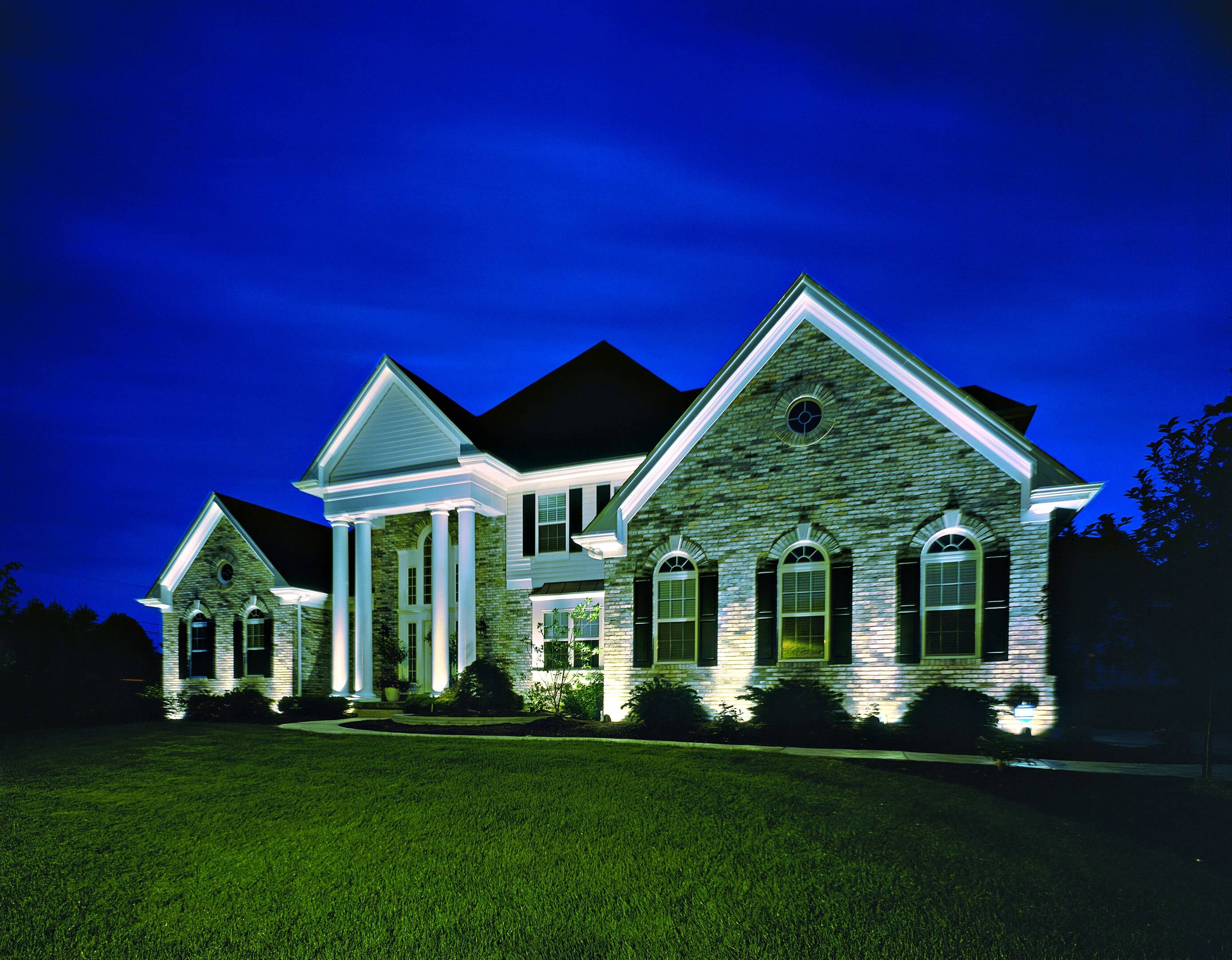 Low-voltage landscape lighting on a home and yard at night