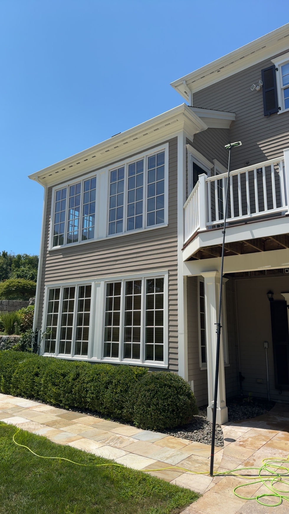 Water-fed pole cleaning the windows of a two-story home