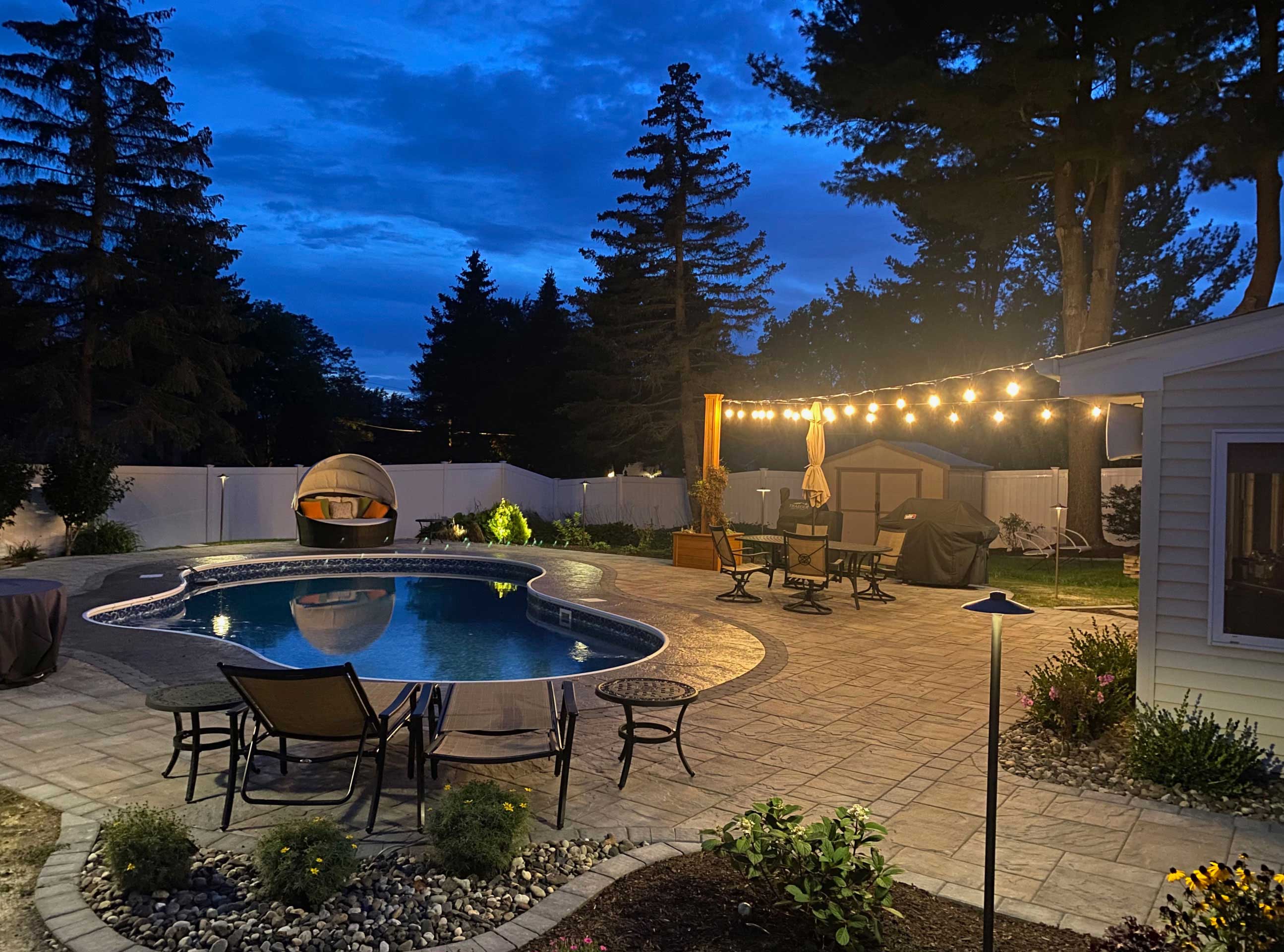Backyard pool and patio under bistro string lights
