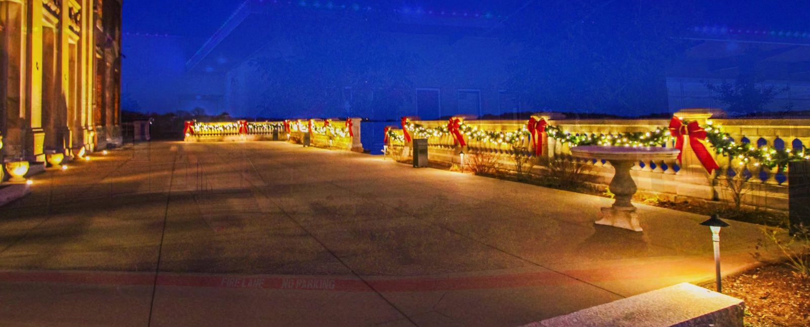 Neighborhood entrance with lighted garland and red bows