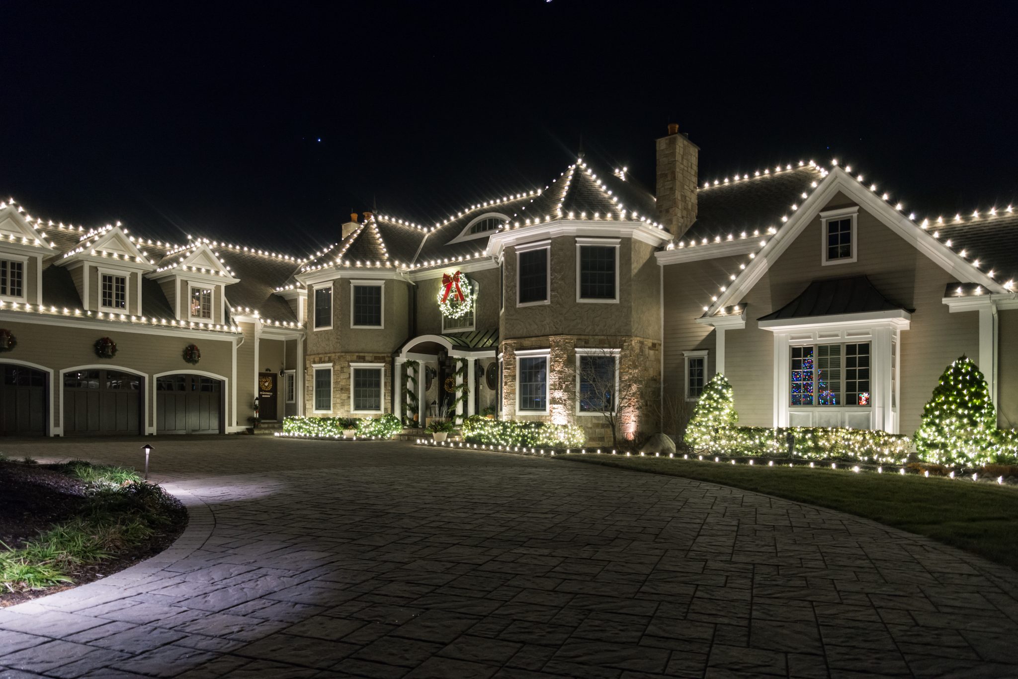 Professionally installed Christmas lights on a home roofline at night