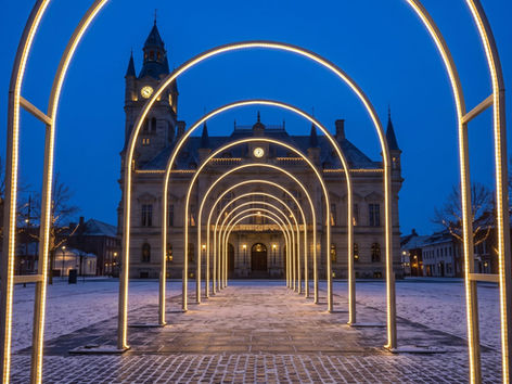 Walk-through tunnel of warm white light arches along a promenade