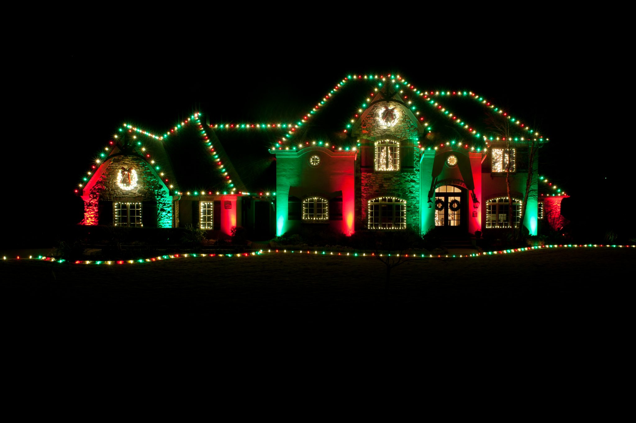 Professionally installed Christmas lights on a home roofline at night