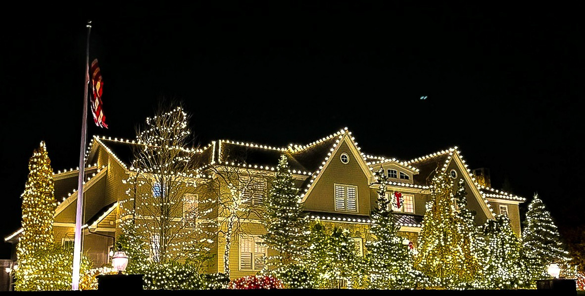 Professionally installed Christmas lights on a home roofline at night