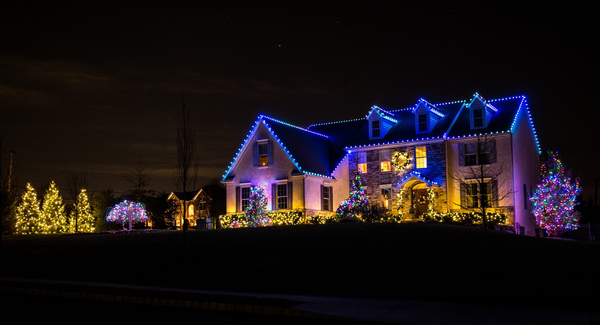 Permanent blue roofline lighting on a two-story home at night
