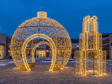 Walk-in 3D ornament and stacked gift box light sculptures on a shopping plaza