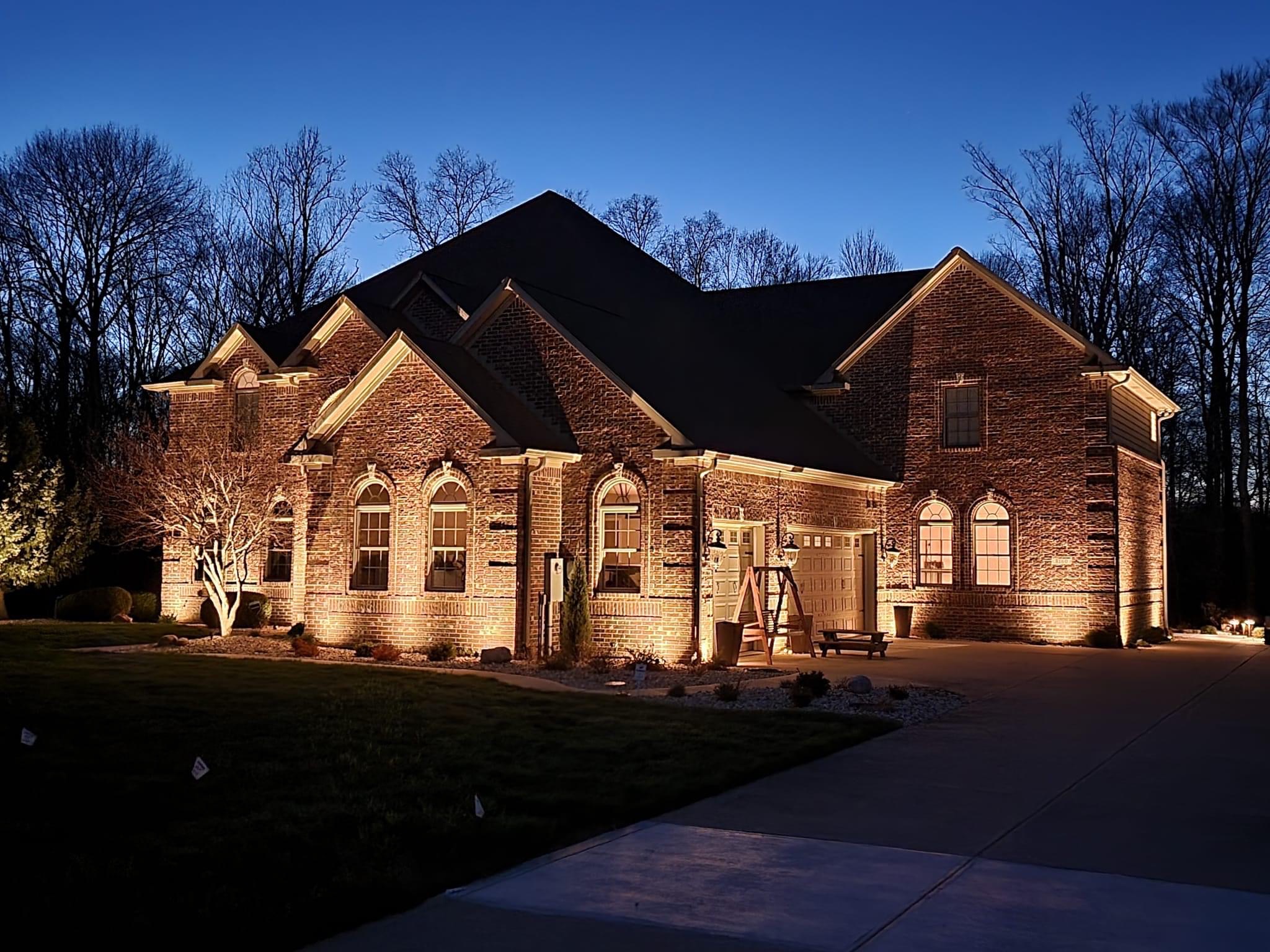 Brick home at dusk with warm landscape and facade lighting