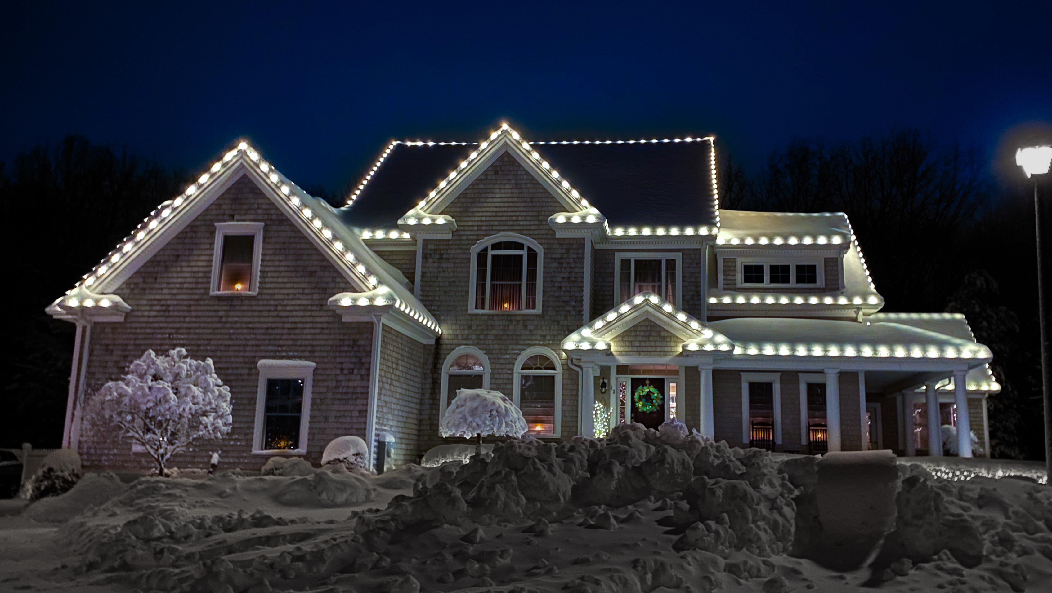 Two-story home outlined in warm white Christmas lights