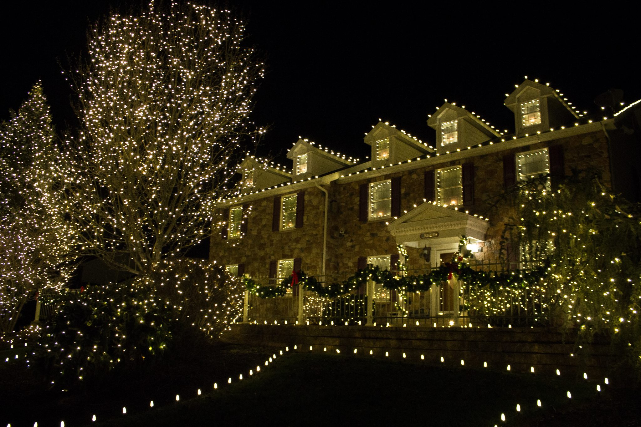 Professionally installed Christmas lights on a home roofline at night