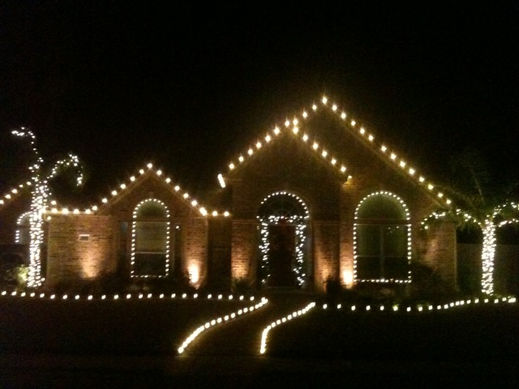 Home roofline and walkway outlined in warm white Christmas lights
