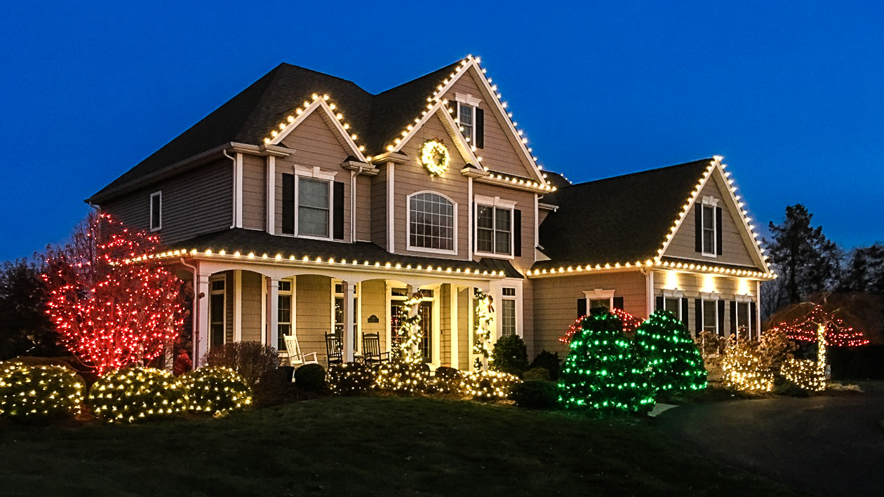 Professionally installed Christmas lights on a home roofline at night
