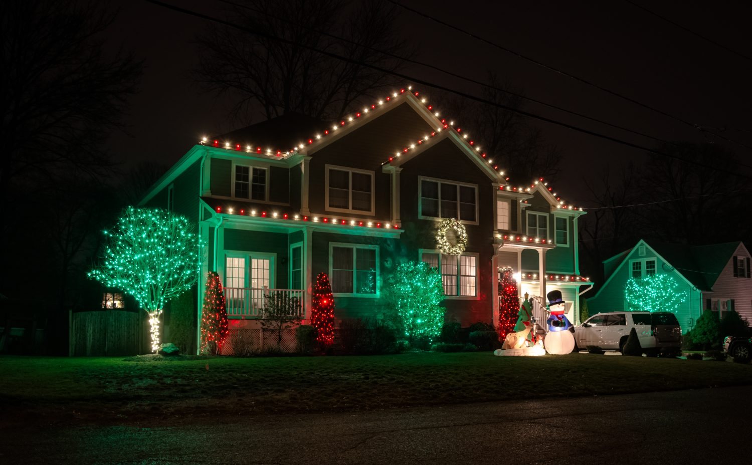 Professionally installed Christmas lights on a home roofline at night