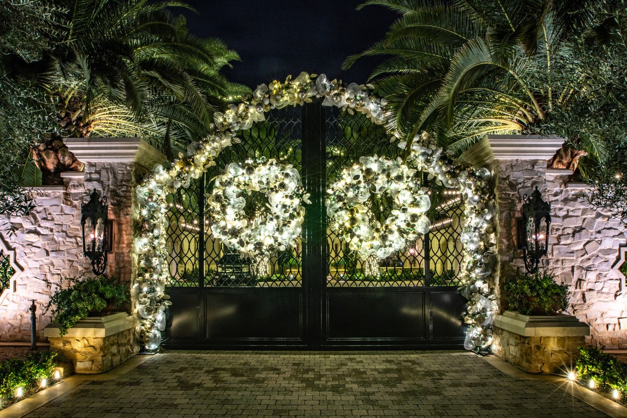 Gated entry with palms, wreaths and garland lights