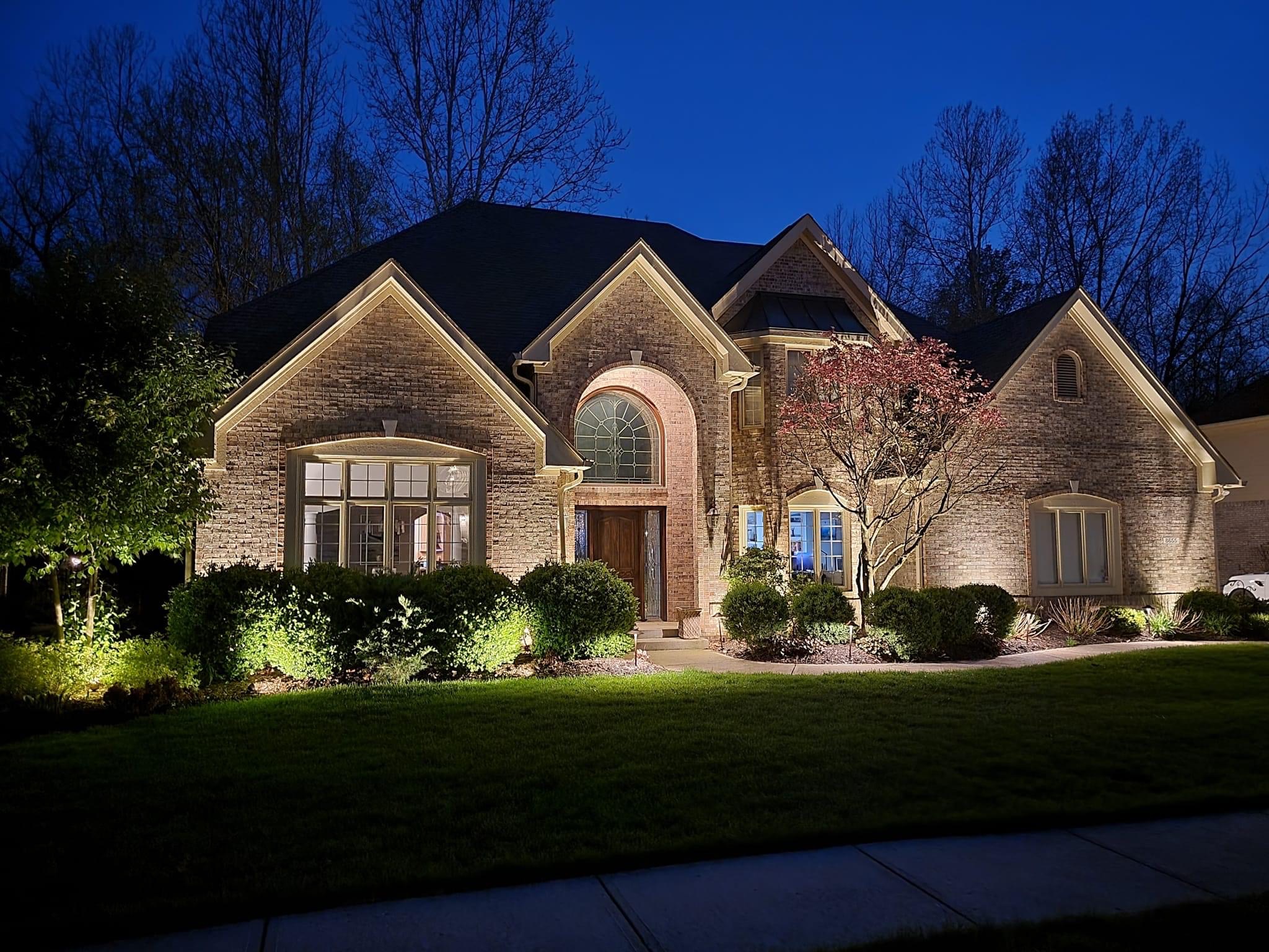 Brick home with facade uplighting and lit planting beds
