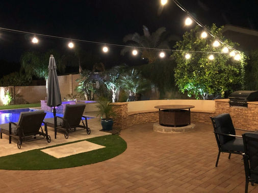Backyard patio and fire pit under bistro string lights