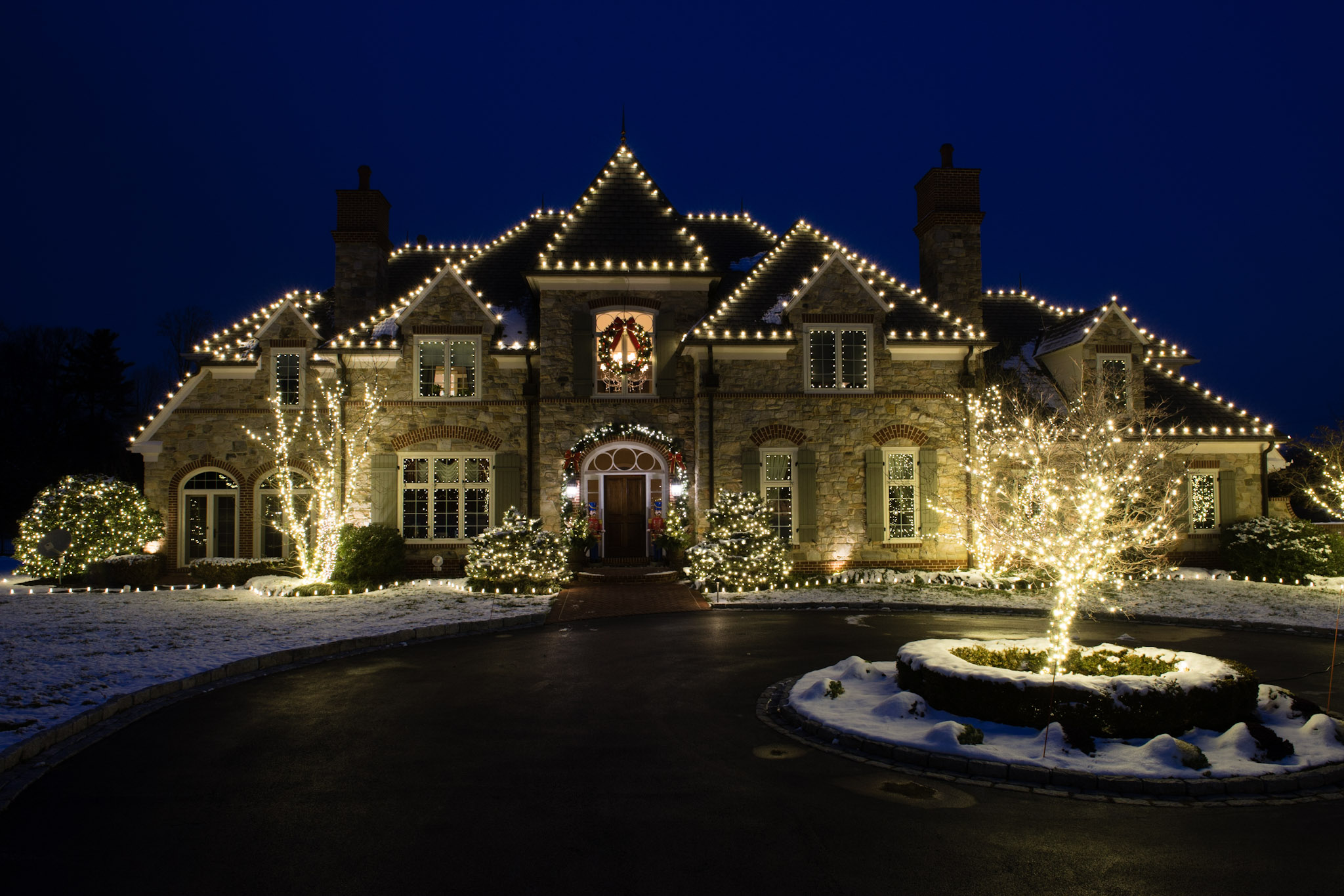 Professionally installed Christmas lights on a home roofline at night