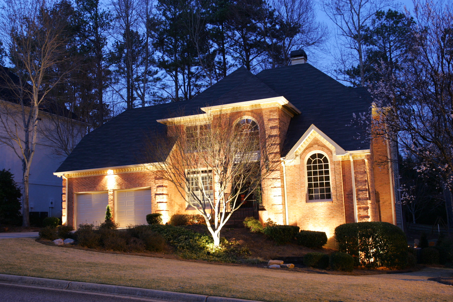 Low-voltage landscape lighting on a home and yard at night