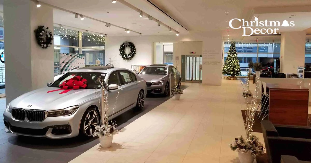 Car dealership showroom with a lit Christmas tree and red bow