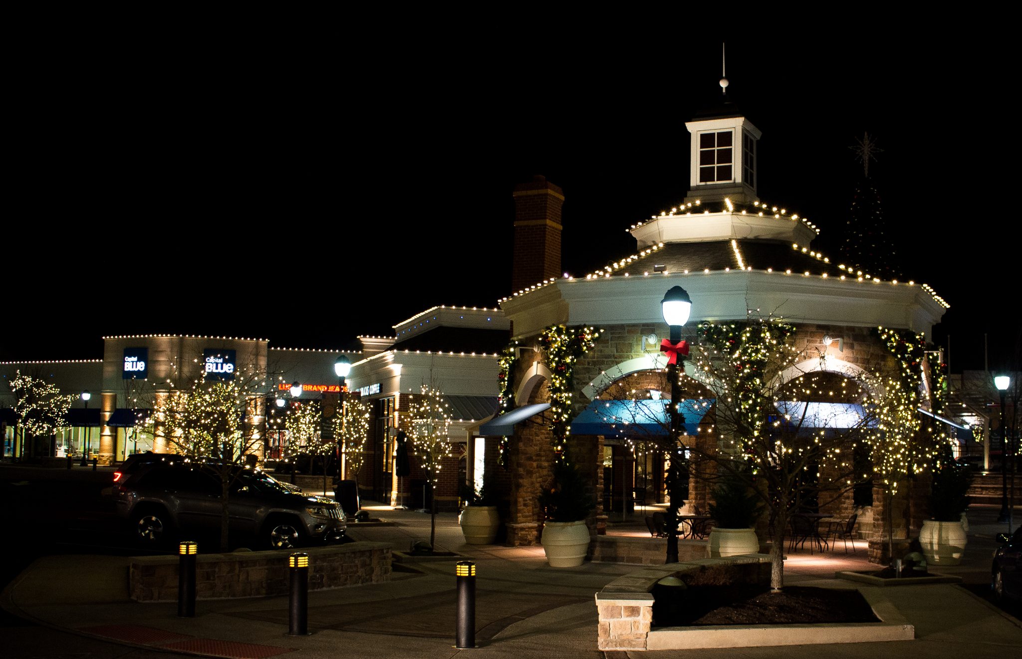 Commercial building and plaza decorated with Christmas lights at night