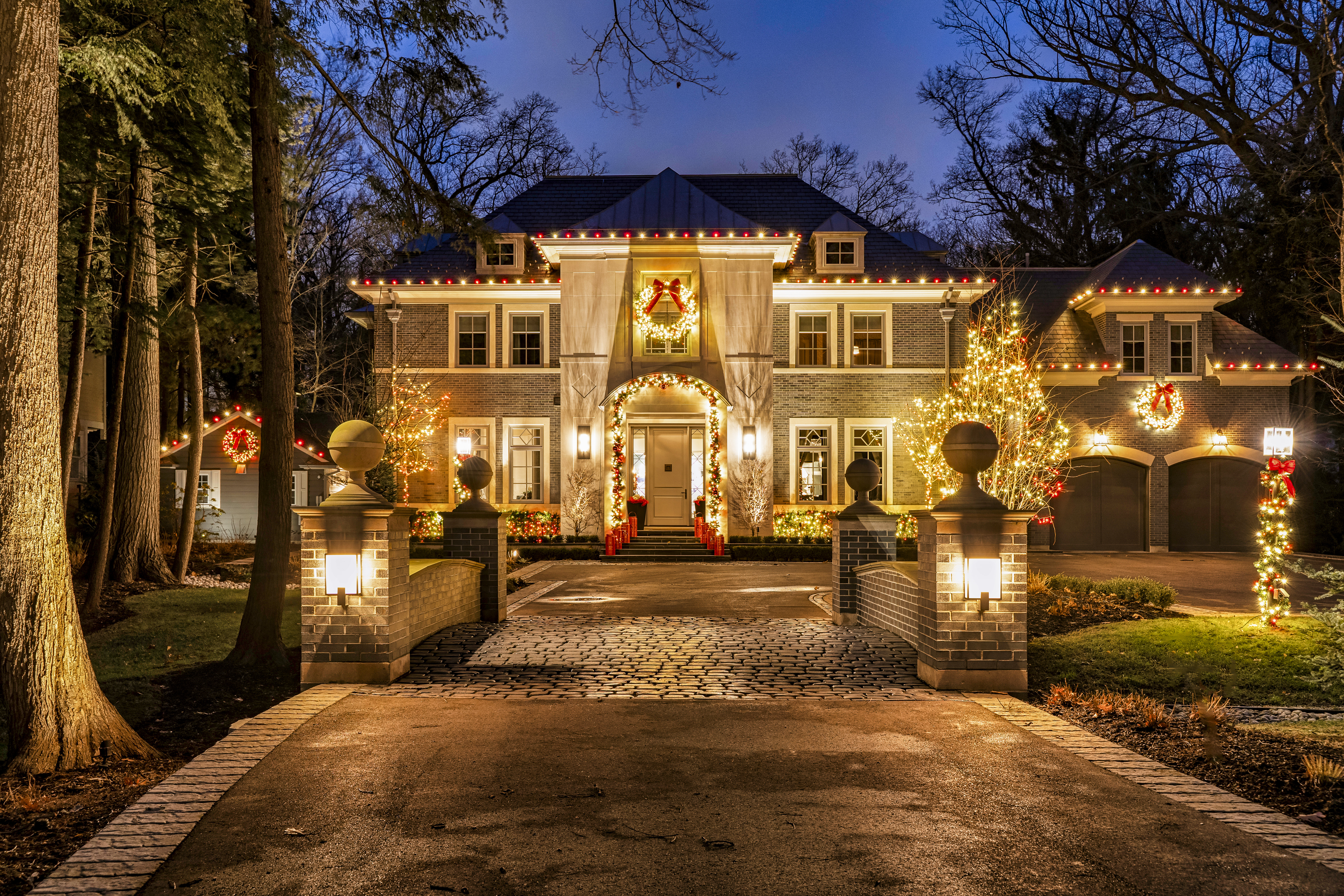 Large home with roofline lights and wreaths
