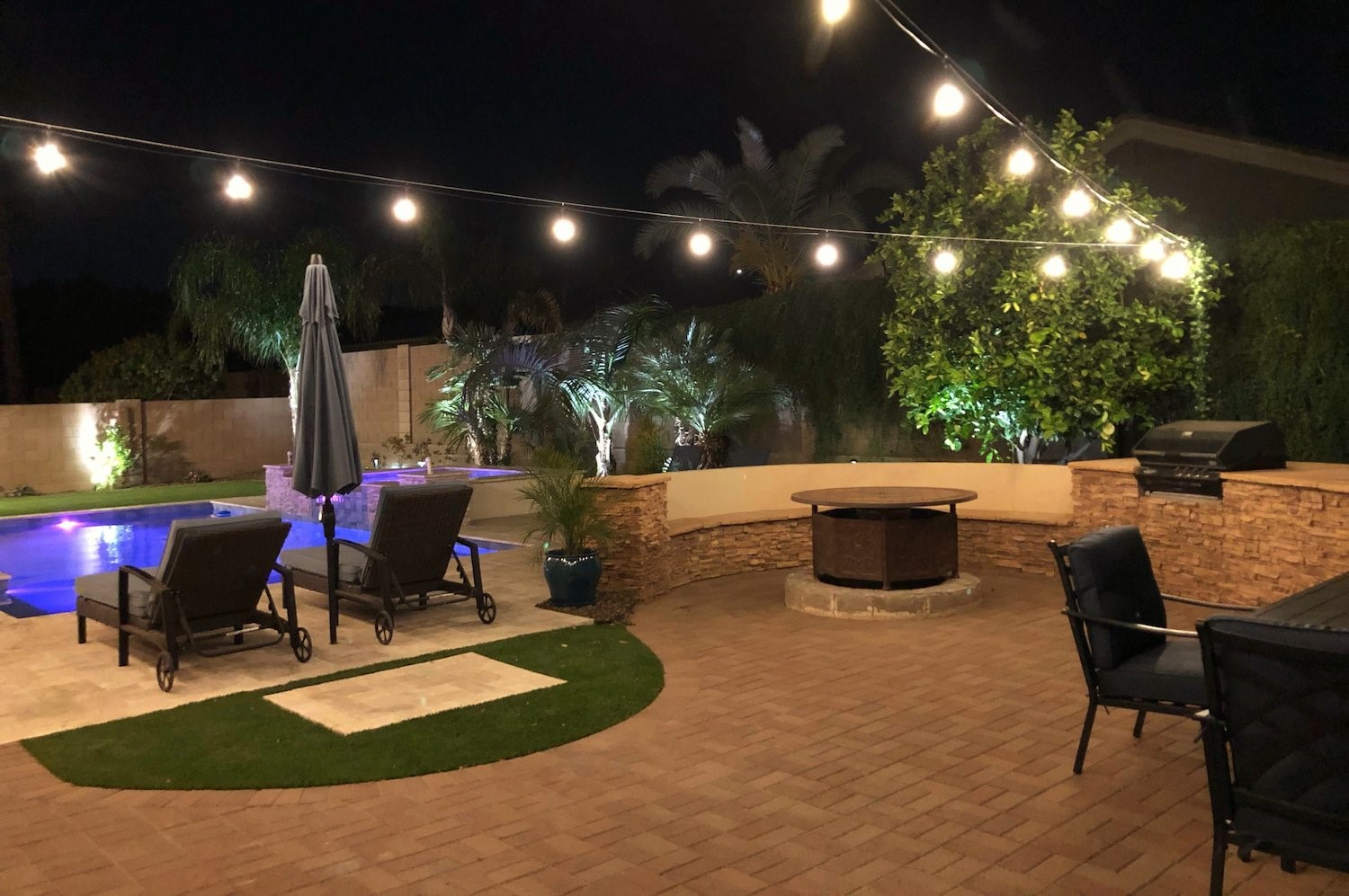 Backyard lawn and fire pit under string lights