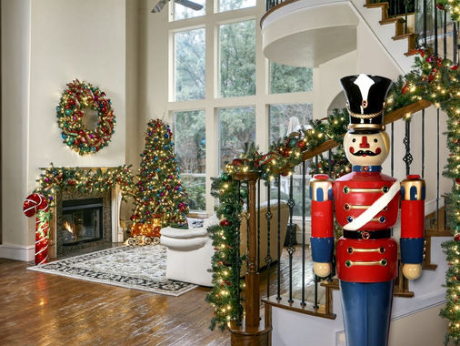 Home foyer with garland on the staircase, a decorated tree and wreath