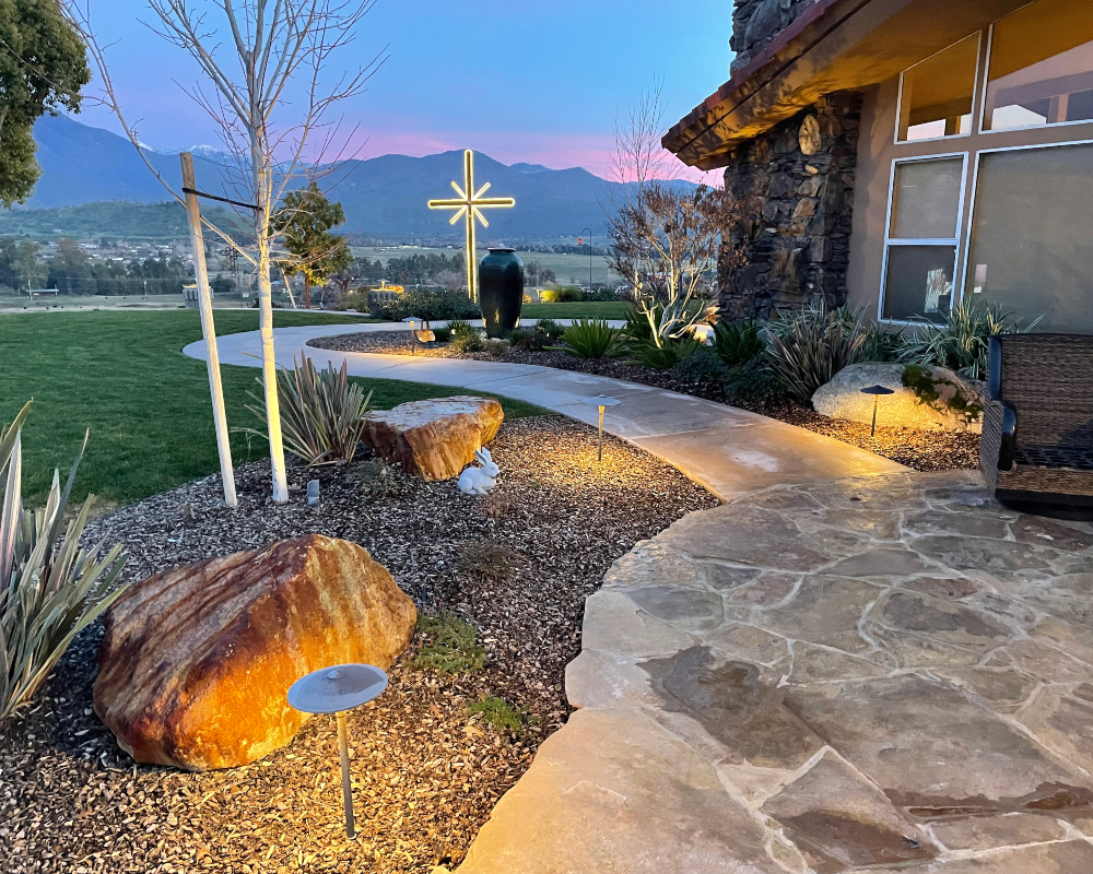 Lit stone pathway through a hillside garden with mountain views