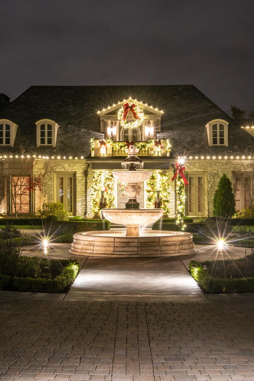 Bonadelle home with a lit fountain, wreaths and roofline lights