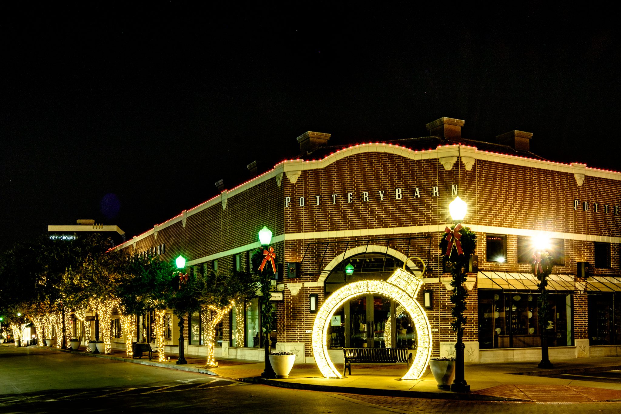 Brick storefront building outlined in Christmas lights with a lighted arch entrance