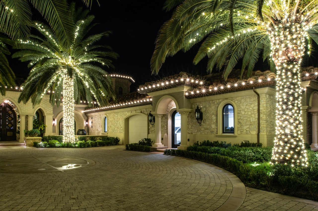 Mediterranean estate with palms wrapped in warm-white lights