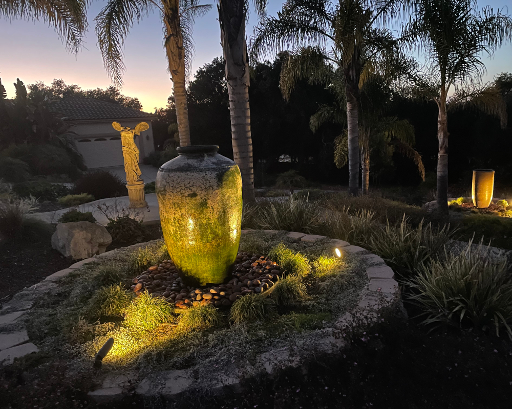 Uplit garden fountain framed by palms