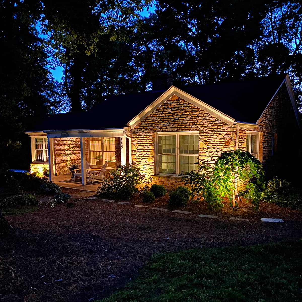 Stone cottage with garden uplighting at night