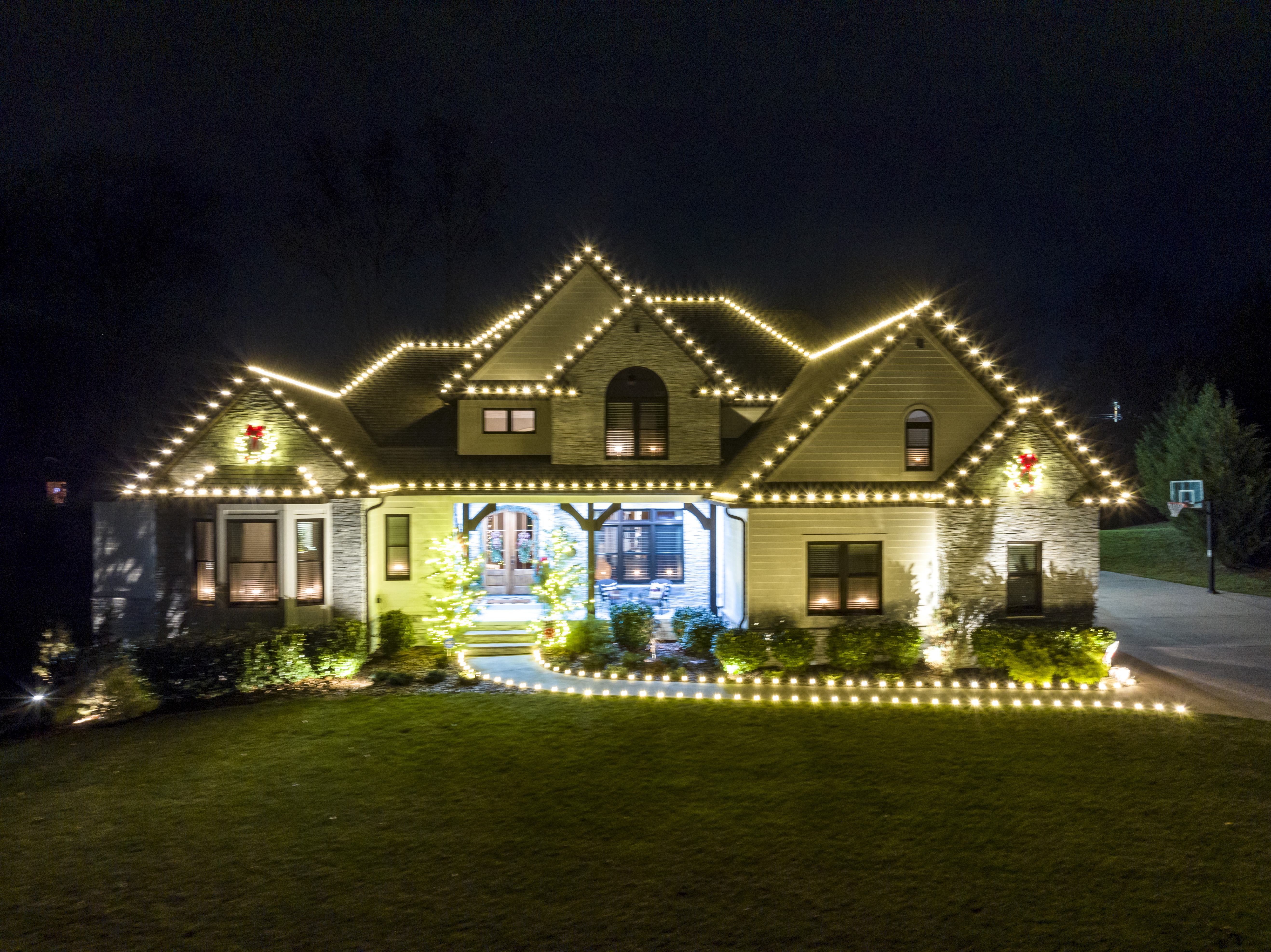 Home with roofline lights over a lit lawn