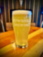 This is either an image of a pint glass filled with the craft beer along with a hand drawn character specific for that brew or, it's the Downhill Brewing logo if there isn't a photo of the brew in a pint glass available.