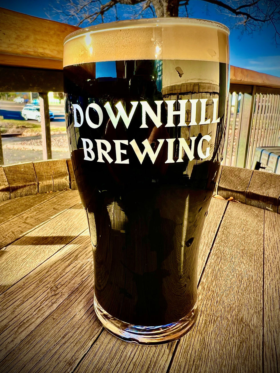 This is either an image of a pint glass filled with the craft beer along with a hand drawn character specific for that brew or, it's the Downhill Brewing logo if there isn't a photo of the brew in a pint glass available.