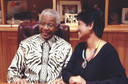 Black and white photo of Pregs Govender and Nelson Mandela at Pregs' 'favourite book reading'. Pregs is sitting with Madiba and smiling.