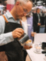 Barista gießt einen Cappuccino in eine Tasse