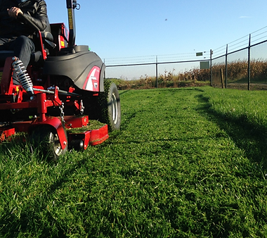 Recon Landscaping mowing a residential lawn in Kennebunk, Maine with clean, professional stripes
