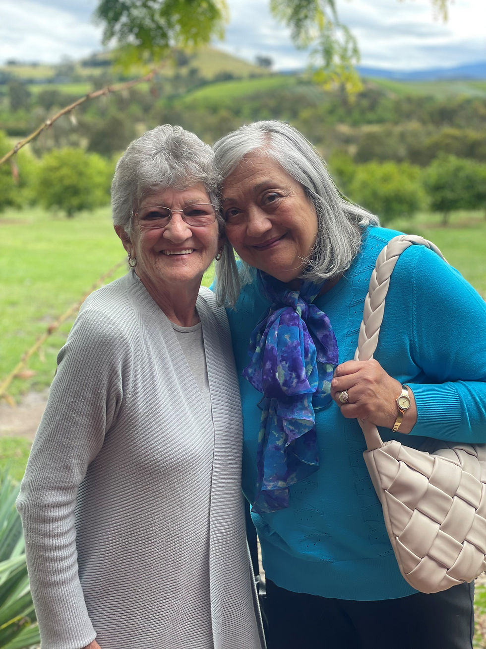 Two older ladies standing in a garden