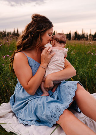Mother holding newborn baby during a golden hour outdoor family session in Red Deer Alberta near Calgary
