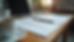 Eye-level view of a cluttered desk with a laptop, resume drafts, and a coffee cup