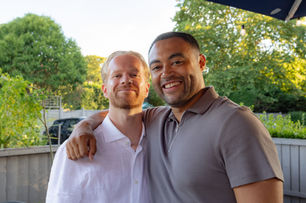 Smiling groom and guest at an outdoor wedding.