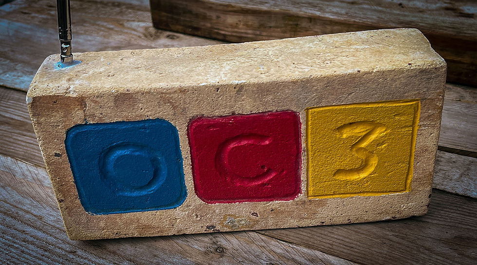 Première brique OC3 portant les trois couleurs du projet, remise dans le cadre du chantier du Pavillon Octroi.
