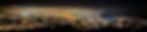 City skyline at night, lights glowing under a cloudy sky. Fog drapes over buildings, creating a mysterious and serene atmosphere.
